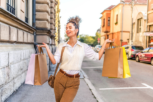 Young beautiful smiling woman with shopping bags in the city