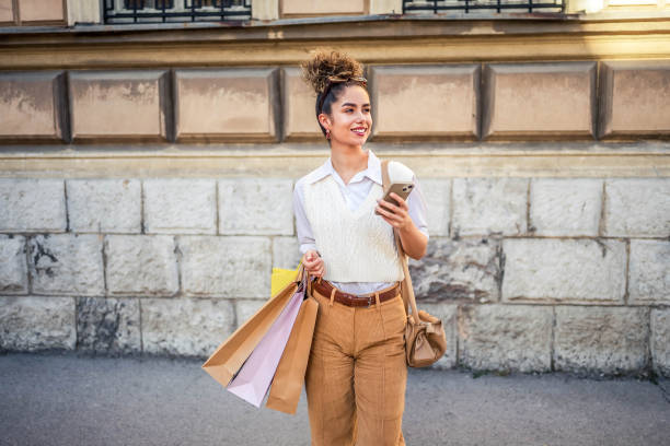 istock Woman using a mobile phone and carrying shopping bags 1778133637