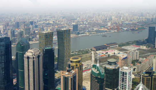 shanghai skyline in cloudy day, showing the Huangpu river with passing cargo ships, financial district and cloudy sky background