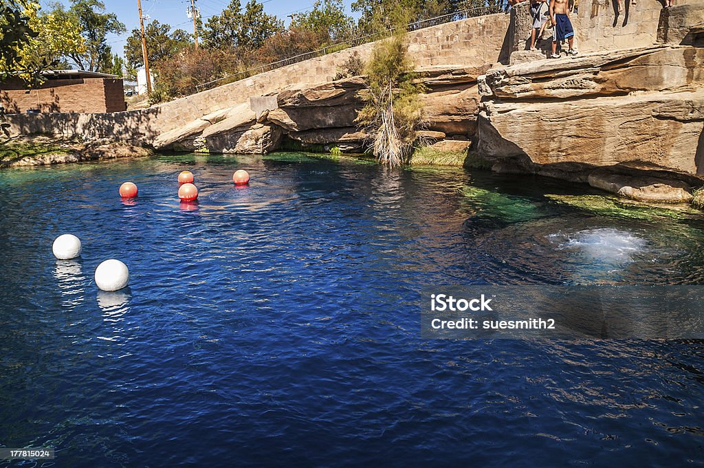 Blue Hole on Route 66 At a depth of 80 feet with clear blue water, the Blue Hole on Route 66 in Santa Rosa, New Mexico, attracts divers and plenty of others looking to cool off on a hot day.  One person just jumped into the pool from the rock ledge creating the rings of ripples. New Mexico Stock Photo