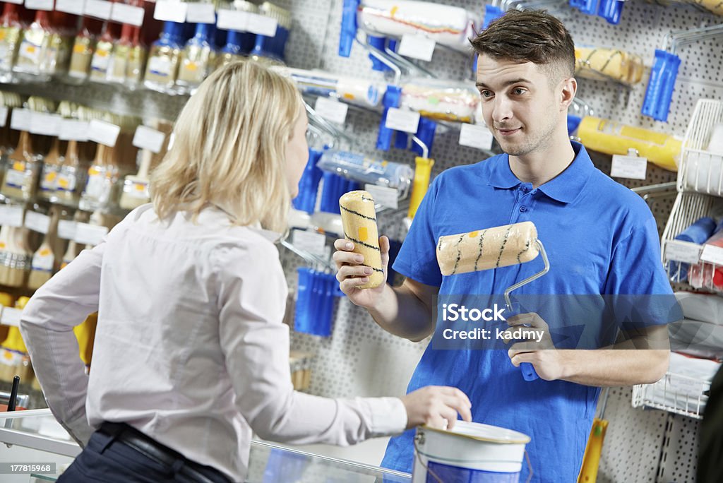 Seller demonstrating paint roller to buyer Assistant seller help buyer by demonstrating paint roller for painting at hardware store Selling Stock Photo