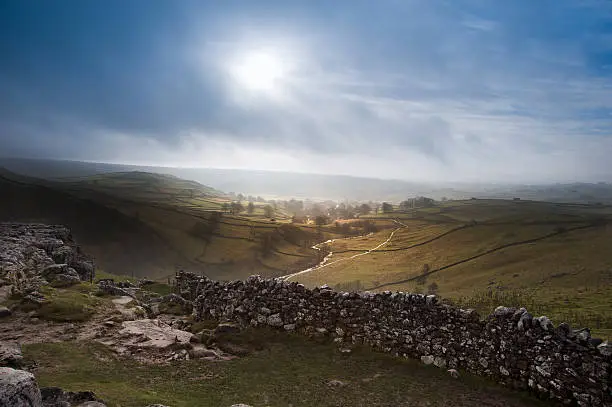 Sunrise over Malham Cove and Dale in Yorkshire Dales National Park with sunlight bursting through mist