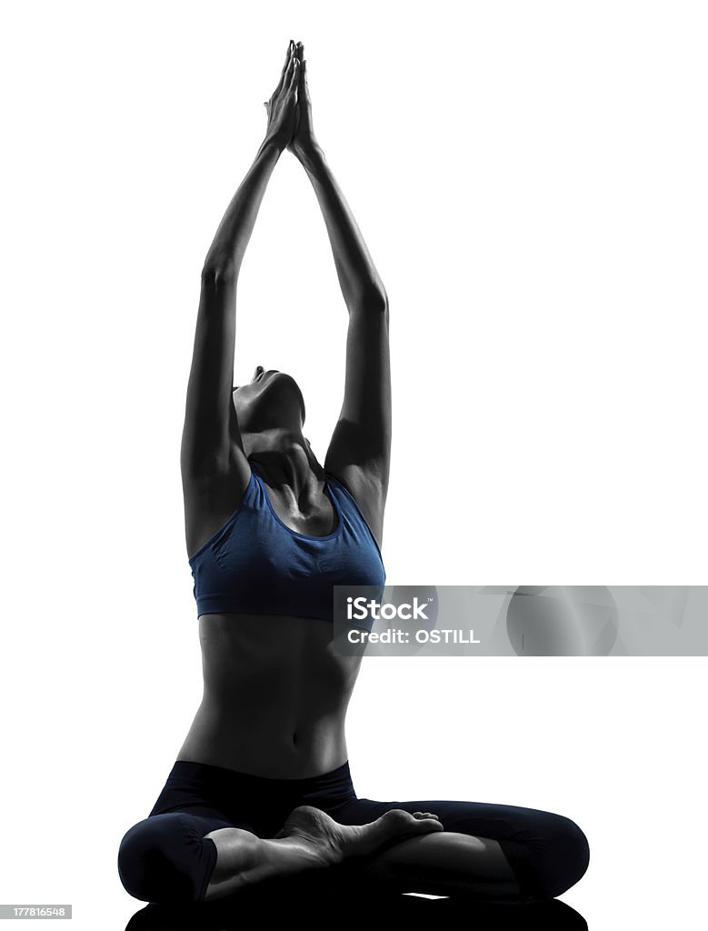 Woman in yoga pose stretching her arms into the sky one caucasian woman exercising yoga meditating sitting hands joined in silhouette studio on white background Yoga Stock Photo