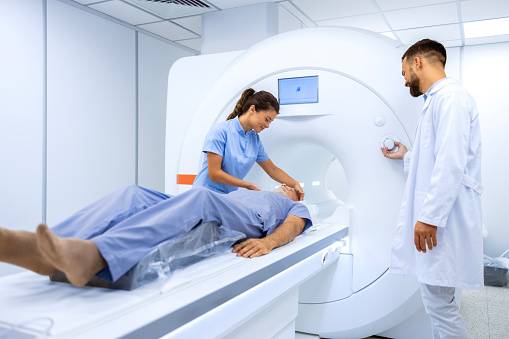 Doctors performing MRI scanning test on senior patient in hospital.