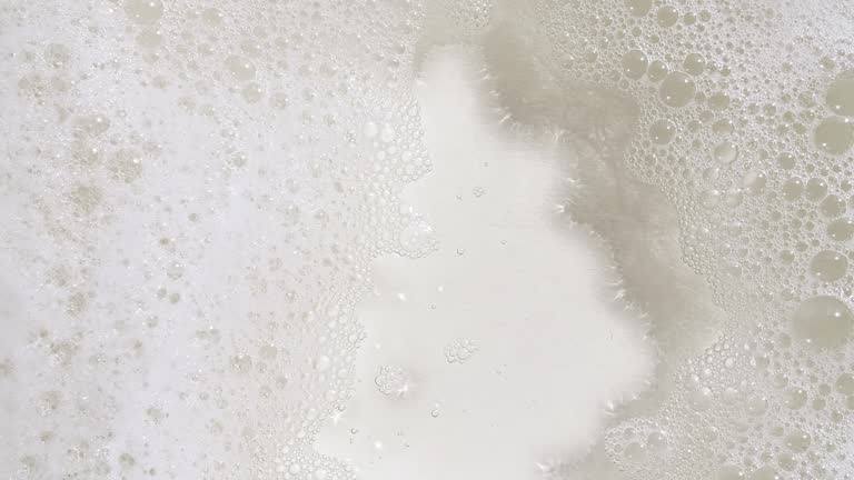 Bubbles of white soap foam on a blue background. Bathtup Soap Foam. Texture of Soap Foam Bubbles. Natural White Shampoo Bubbles Motion