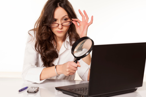 suspicious secretary in white shirt did found something on her laptop with a magnifying glass
