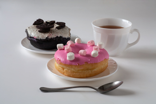 There are donuts in plates on the table. There is a spoon in front of them.