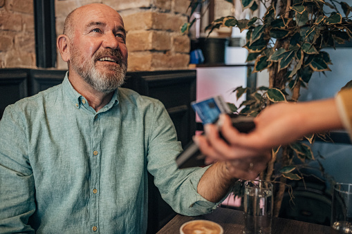 Mature man paying with credit card In the cafe