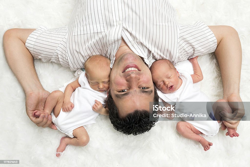 Daddy with twins Happy daddy posing with his newborn twin sons Twin Stock Photo