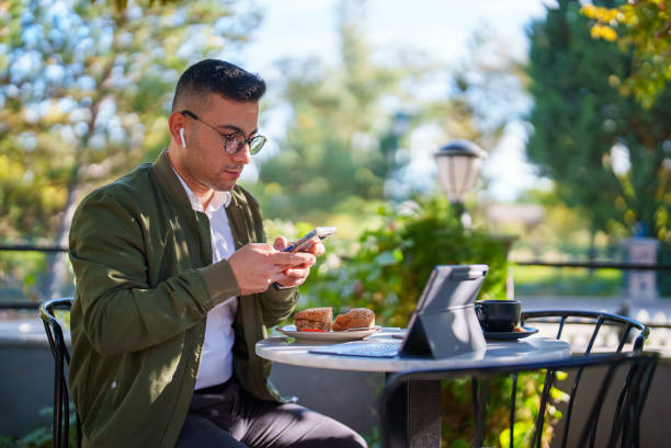 Freelance Businessman working on mobile phone and digital tablet at a cafe stock photo