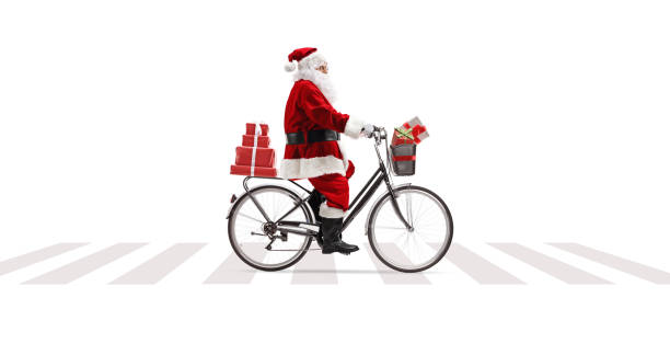 full length profile shot of santa claus riding a bicycle at a pedesrian crossing and carrying presents - bicycle isolated basket red imagens e fotografias de stock