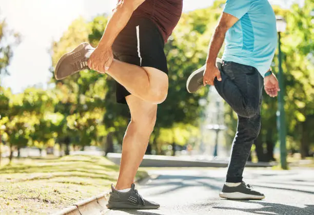 People, friends and stretching legs in park for running, exercise or outdoor training together in nature. Men in body warm up, leg stretch or preparation for cardio workout or team fitness outside