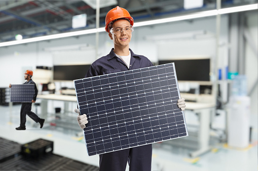 Workers inside a factory carrying solar panels, manufacturing industry concept