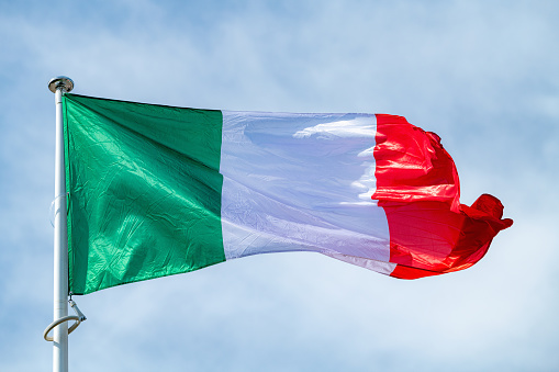 The national flag of Italy waving in the blue sky