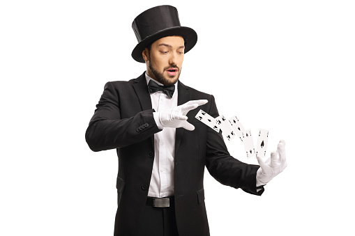 Magician wearing white gloves and performing a trick with flying cards isolated on white background