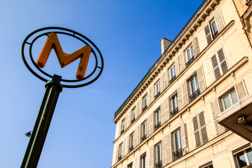 Metro sign in Paris against clear blue sky and with parisian building on the background, Paris, France