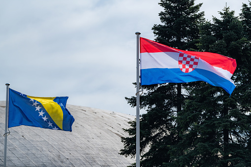 The national flags of Croatia and Bosnia and Herzegovina waving in the blue sky