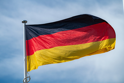 The national flag of Germany waving in the blue sky