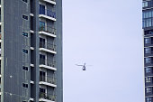 Helicopter Flying amongst Modern Buildings on Overcast Sky