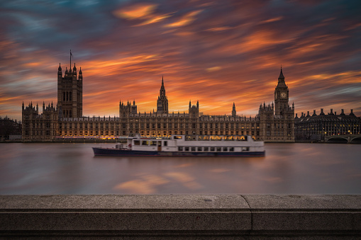 sunset behind the Houses of Parliament and the Big Ben along the Thames river at dusk; London, United Kingdom