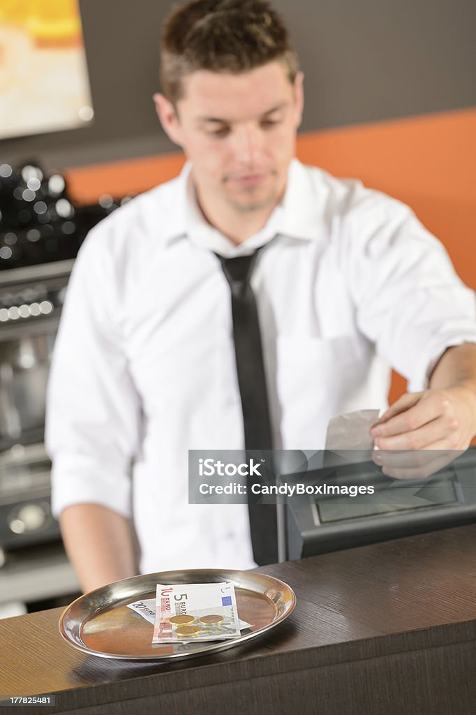 Young bartender in uniform taking cash euro Young bartender in uniform taking cash EUR in bar Gratuity Stock Photo