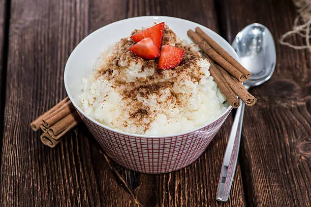 Rice Pudding with Cinnamon and Strawberries on wooden background