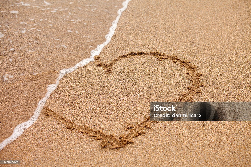 Cuore sulla sabbia taked da onde - Foto stock royalty-free di Affettuoso