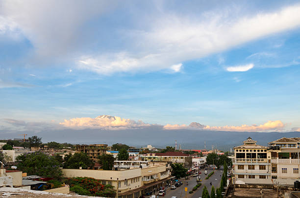 View over Moshi at sunset with Mount Kilimanjaro and Mawenzi Moshi, Tanzania is the town most climbers will stay before they start their journey to climb Kilimanjaro. Moshi is located at an elevation of about 800 m AMSL and Kilimanjaro in the back (left), is the highs mountain in Africa with its 5895 m AMSL. To the right of Kilimanjaro is Mount Mawenzi. mawenzi stock pictures, royalty-free photos & images