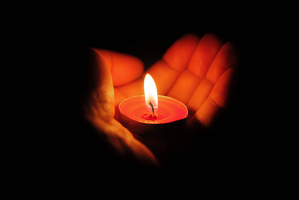 istock left hand holding a burning candle in dark 177830608