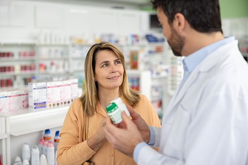 Latin American woman buying medicines at the drugstore and talking to the pharmacist - healthcare and medicine concepts