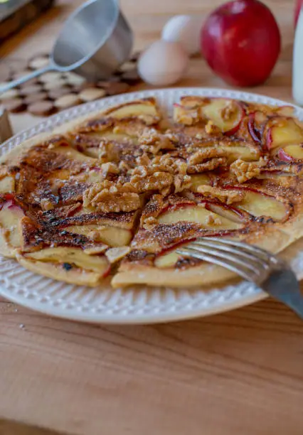 German cuisine with fresh pan fried egg pancake with caramelized apples and walnuts on a plate on rustic table background.