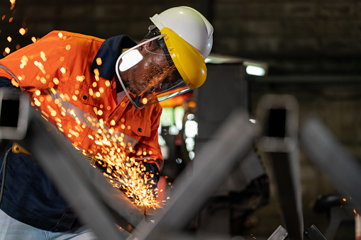 Skilled worker crafts steel with precision and dedication. As a shower of sparks flies in all directions, it illuminates a scene of metalworking artistry, a sparks and steel. Craftsman in protective gear operates an angle grinder with unwavering skill.