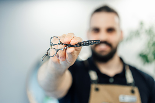 Close-up of barber holding a pair of scissors in hand