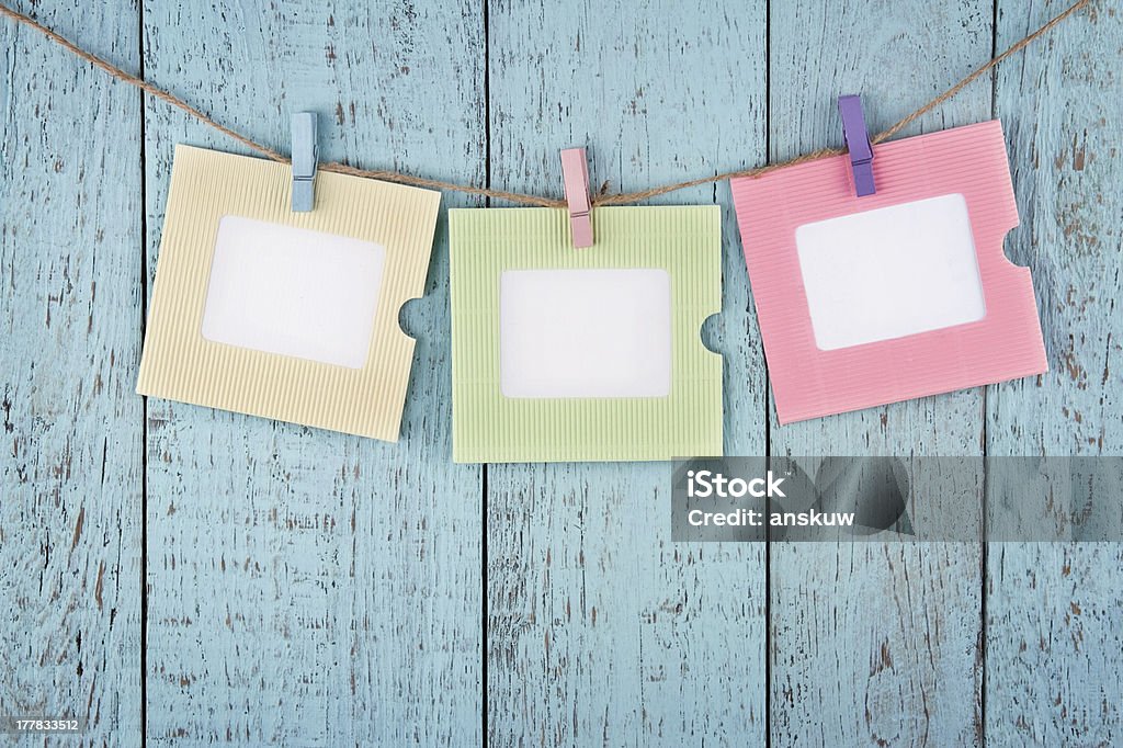 Three empty photo frames hanging with clothespins Three empty colorful photo frames or notes paper hanging with clothespins on wooden blue vintage shabby chic background Blank Stock Photo