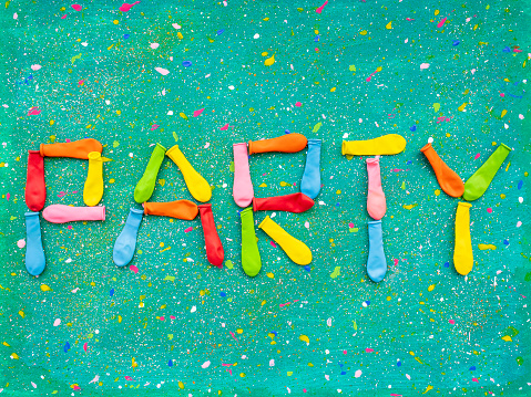 Word Party made of multi colored deflated balloons on abstract spotted background
