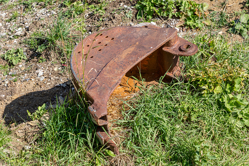 Old rusty excavator shovel on a meadow