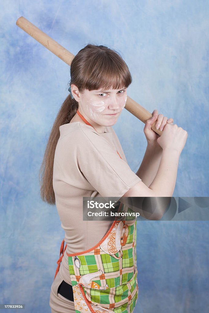 rolling pin Young girl brandishing a rolling pin on a blue background. Adult Stock Photo