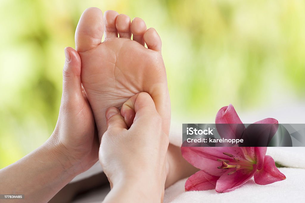 Le mani facendo un trattamento di riflessologia plantare. - Foto stock royalty-free di Riflessologia