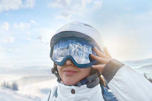 A skier up close on a snowy mountain slope, wearing a sports suit helmet and ski goggles over the blue sky copy space