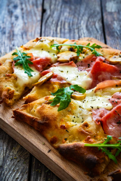 istock Pinsa Romana with ham, mozzarella cheese and white mushrooms on wooden table 1778356319