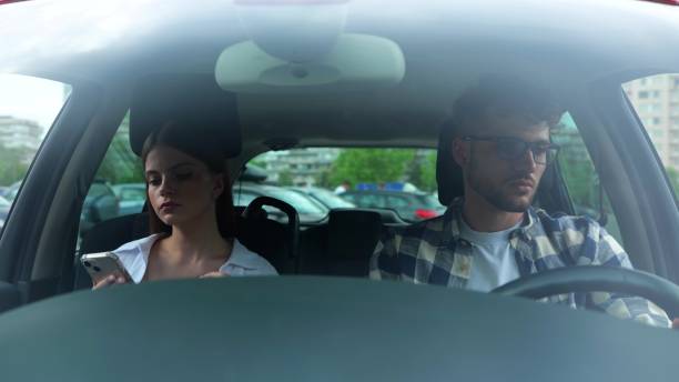 istock Young man driving car while his girlfriend sitting next to him and using mobile phone. Transport, travel, relationships, safety concept. Slow motion 1778357923