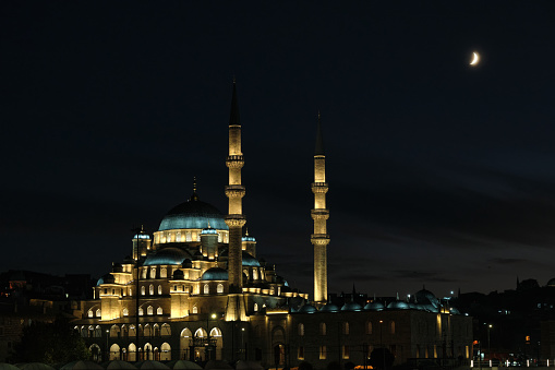A beautiful Muslim mosque of the Byzantine type against the backdrop of the night sky with a crescent moon.