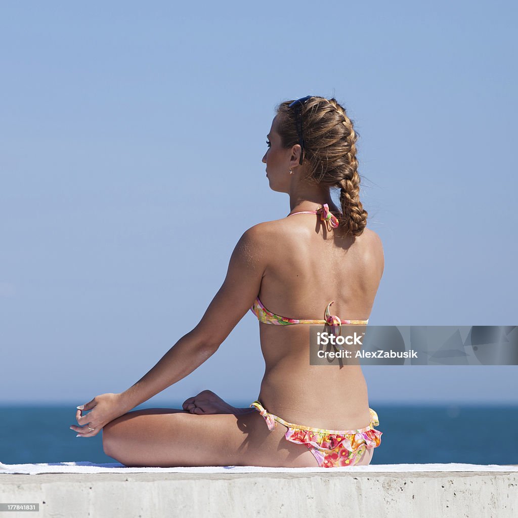 Atractiva mujer en traje de baño haciendo yoga en el mar - Foto de stock de Actividad libre de derechos