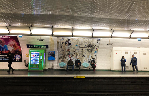 Paris, France: Cleaners chat in Le Peletier metro station as passengers sit waiting for a train.