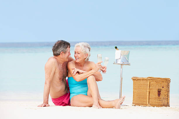 pareja senior en la playa con champán picnic de lujo - men refreshment male summer fotografías e imágenes de stock
