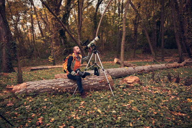 Man using telescope for bird and animal watching in nature.