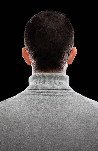 Man with short dark hair and a grey sweater turning his back stock photo