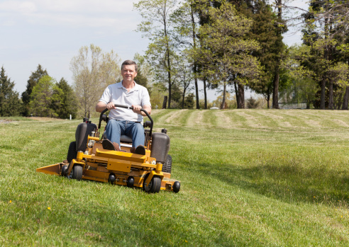 Senior man cutting grass with a lawnmower