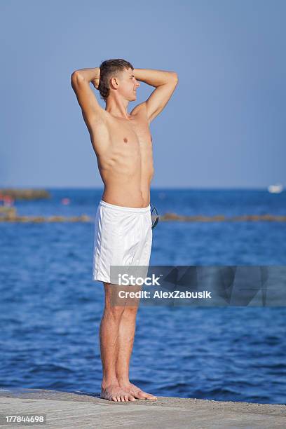 Uomo Con Le Braccia Alzate In Piedi Sul Molo - Fotografie stock e altre immagini di 20-24 anni - 20-24 anni, Abbronzatura, Acqua