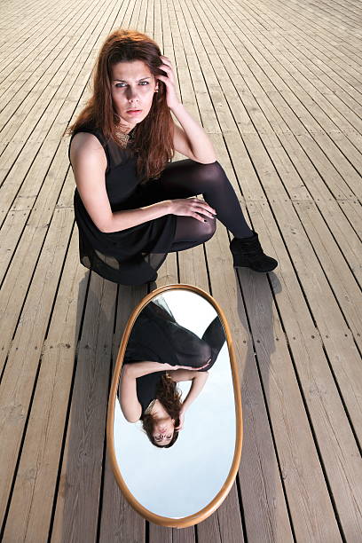 istock thoughtful woman looks at the reflection in mirror 177845295